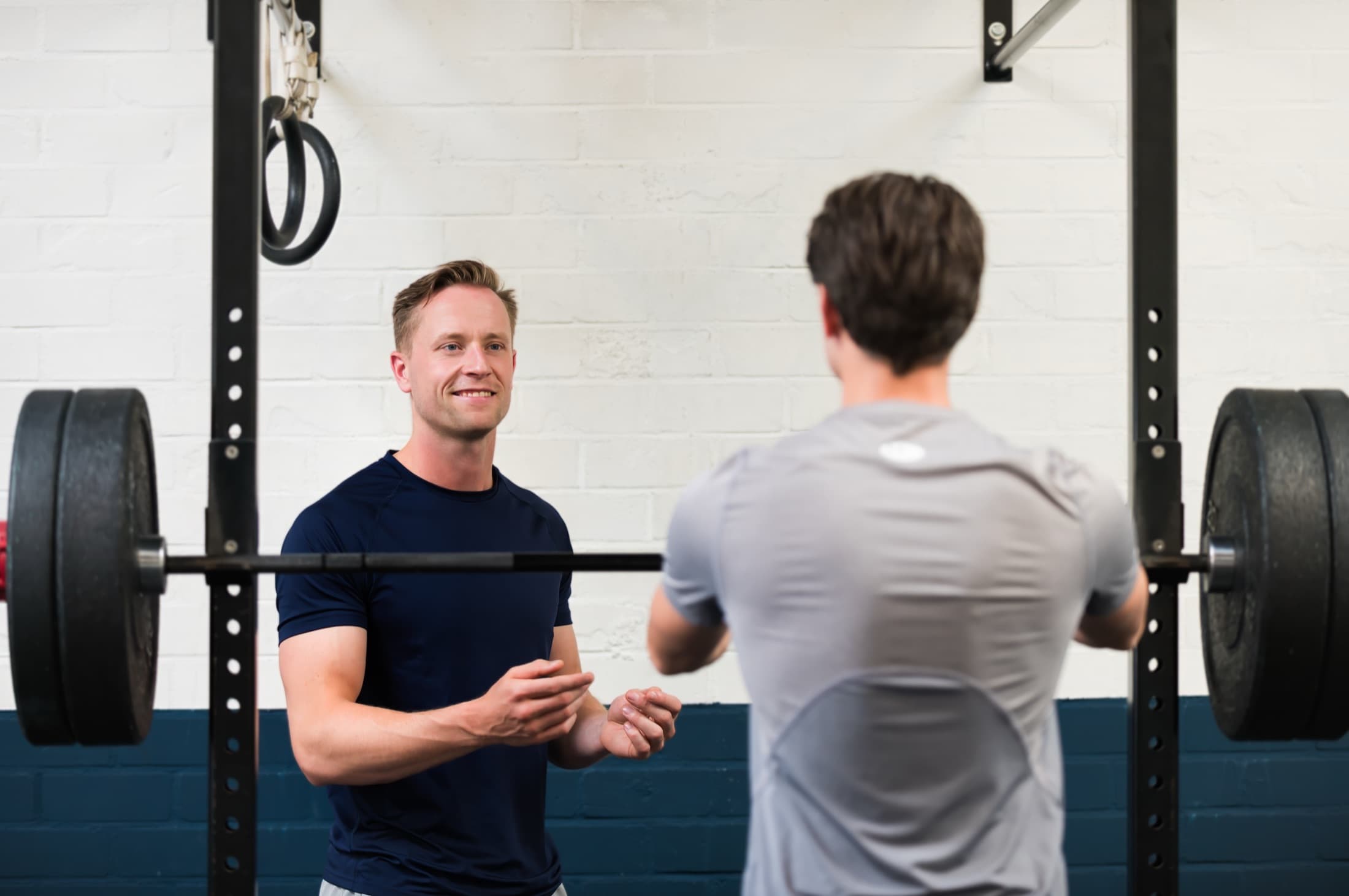 Jelle Stolk coacht een klant bij de squat rack in de studio in Breda